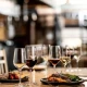 Στρωμένο τραπέζι με ποτήρια κρασιού Zwiesel Cinco και πιάτα φαγητού σε ζεστό ξύλινο φόντο