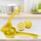 Χρήση του κίτρινου στύφτη λεμονιού χειρός Pedrini στον πάγκο της κουζίνας δίπλα σε φρέσκα λεμόνια.