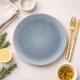 Πιάτο Cryspo Trio Neptune stoneware σε μπλε-γκρι απόχρωση με ακτινωτό σχέδιο σε στρωμένο τραπέζι, μαζί με μαχαιροπήρουνα.