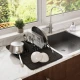 Μαύρη πιατοθήκη Umbra UDry Ultra Black δίπλα στον νεροχύτη με κατσαρόλες, πιάτα και μπολ σε λευκό μαρμάρινο πάγκο κουζίνας
