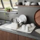Μπεζ πιατοθήκη Umbra UDry Ultra Sand με πιάτα, ποτήρια και κούπες σε γκρι πάγκο κουζίνας δίπλα στον νεροχύτη