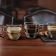 Τρία κρυστάλλινα φλιτζάνια RCR Caffè με lungo και macchiato δίπλα σε κόκκους καφέ.