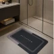 Γκρι πατάκι μπάνιου MRShome από polyester 40x60cm με σχέδιο Bathroom, τοποθετημένο σε ντουσιέρα.