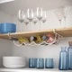 Metaltex Cool-Bottle λευκή θήκη μπουκαλιών κάτω από ξύλινο ράφι κουζίνας με κρασιά και ποτήρια