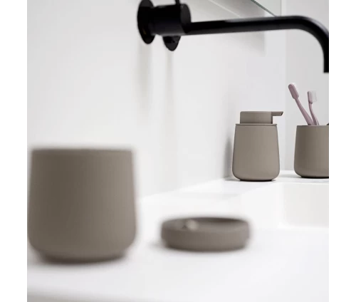 Σύγχρονη διακόσμηση νιπτήρα με το ντισπένσερ σαπουνιού Zone Denmark Nova One σε γήινη απόχρωση Taupe δίπλα σε μαύρη μπαταρία.