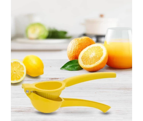 Χρήση του κίτρινου στύφτη λεμονιού χειρός Pedrini στον πάγκο της κουζίνας δίπλα σε φρέσκα λεμόνια, πορτοκάλια και ένα ποτήρι χυμό.
