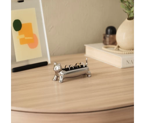 Ασημί μεταλλική βάση κοσμημάτων Umbra Ali Cat σε σχήμα γάτας σε τραπεζάκι δίπλα από κορνίζα.