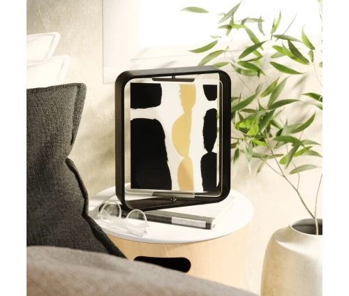 Μαύρη επιτραπέζια κορνίζα Umbra Bellwood με καμπυλωτό ξύλινο πλαίσιο σε τραπεζάκι.