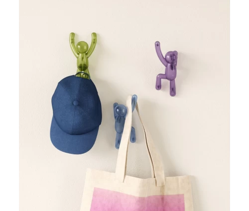 Σετ από τρεις κρεμάστρες τοίχου Umbra Buddy σε σχήμα ανθρώπινης φιγούρας που αναρριχάται σε μπεζ τοίχο.