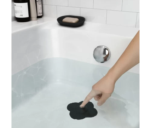 Μαύρη τάπα σιλικόνης Umbra Bloom σε σχήμα λουλουδιού, τοποθετημένη σε σιφόνι νιπτήρα μπάνιου.