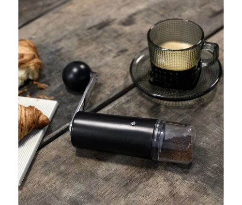 Χειροκίνητος μύλος άλεσης κόκκων καφέ Colombia της CrushGrind, με αποσπώμενη λαβή τοποθετημένος σε τραπεζάκι μαζί με φλυτζάνι καφέ.