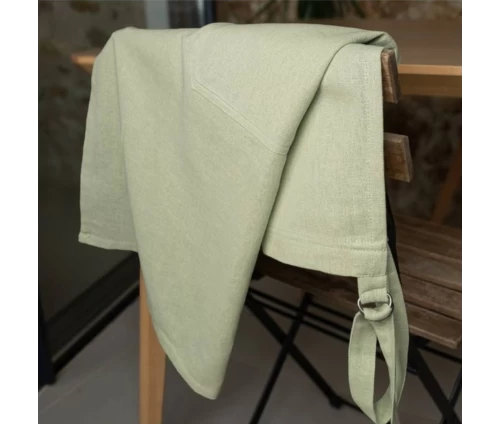 Παστέλ πράσινη ποδιά Finesse CHEF ριγμένη κομψά σε μια ξύλινη καρέκλα.