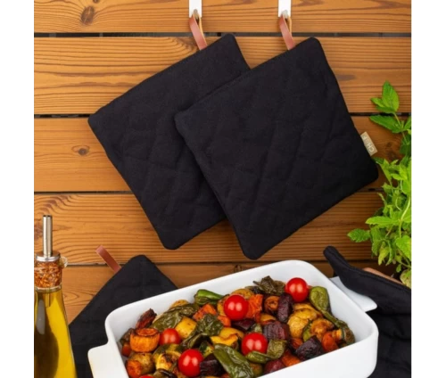 Μαύρη βαμβακερή καπιτονέ πιάστρα Finesse CHEF BBQ, κρεμασμένες μπροστά από ταψί.