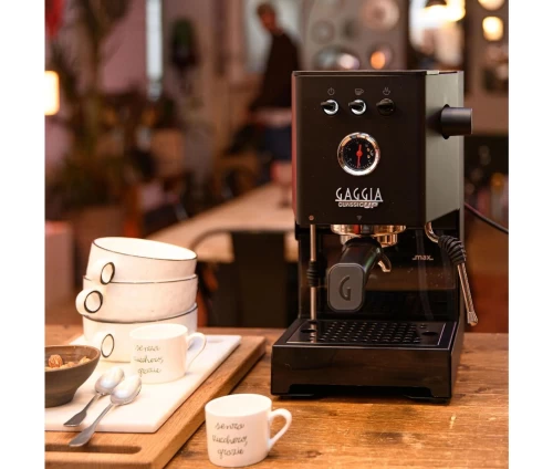 Gaggia Classic Up Black manual espresso machine με μανόμετρο και οθόνη TFT, σε σύγχρονη κουζίνα μαζί με φλυτζάνια.