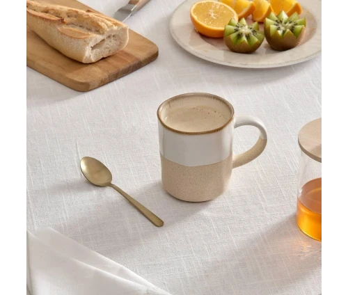 Δίχρωμη κούπα Kate της Secret de Gourmet σε λευκό και μπεζ χρώμα πάνω σε στρωμένο τραπέζι πρωινού.