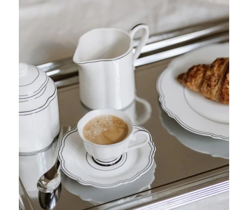 Λευκή γαλατιέρα Salt&Pepper Odette με κυματιστό σχέδιο και μαύρο περίγραμμα σε δίσκο μαζί με φλυτζάνι και ζαχαριέρα.